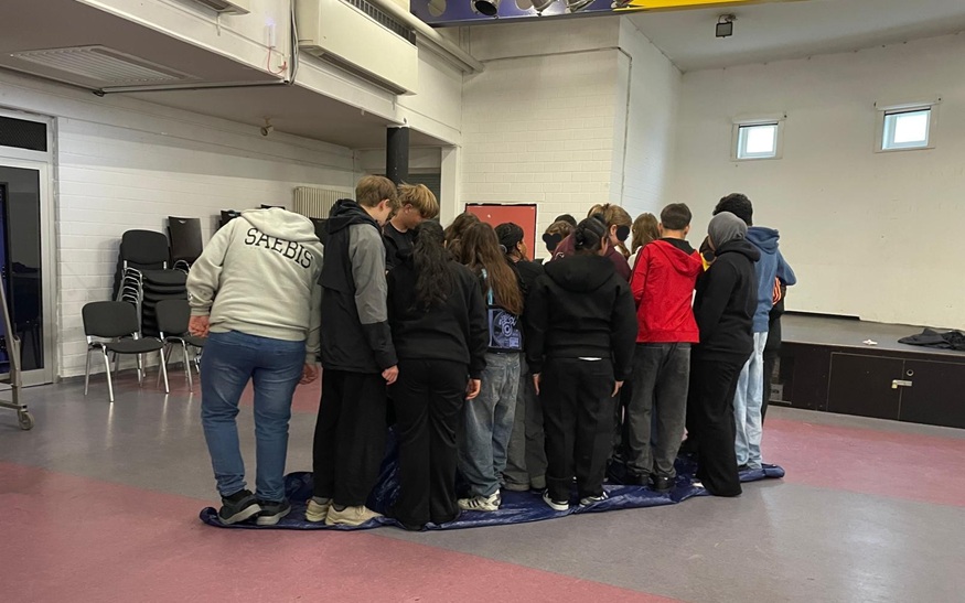 Beim "Plane wenden" müssen die Schülerinnen und Schüler der achten Klasse zusammen arbeiten. Keiner darf runter - das ist ein Balanceakt. Beim "Plane wenden" müssen die Schülerinnen und Schüler der achten Klasse zusammen arbeiten. Keiner darf runter - das ist ein Balanceakt.