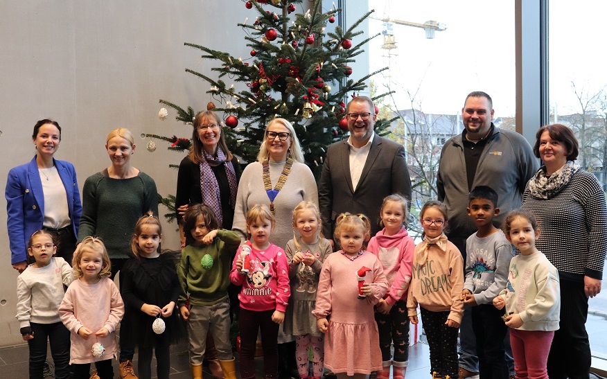 Zum Auftakt der Wunschweihnacht hat Oberbürgermeister Nico Lauxmann gemeinsam mit Liane Haufe (Mitte), Präsidentin des Lions Clubs, Eyleen Erlenmaier (links), vom städtischen Stadtmarketing, sowie den Kindern der städtischen Kindergärten in der Bebelstraße und der Kirchstraße den Weihnachtsbaum geschmückt. 